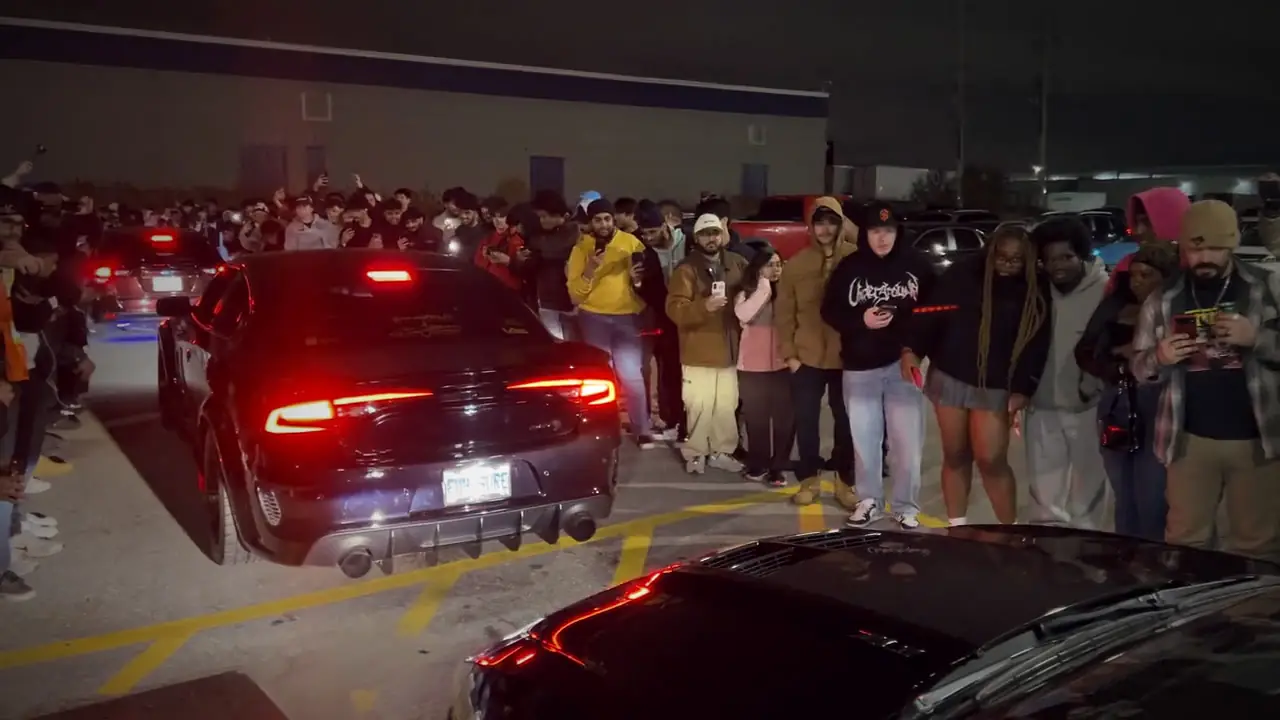 Feux arrière rouges et foule lors d'un meeting de nuit