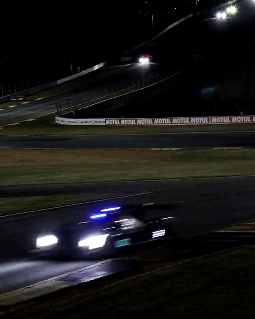 Voiture de course phares allumés dans un virage, de nuit sur circuit